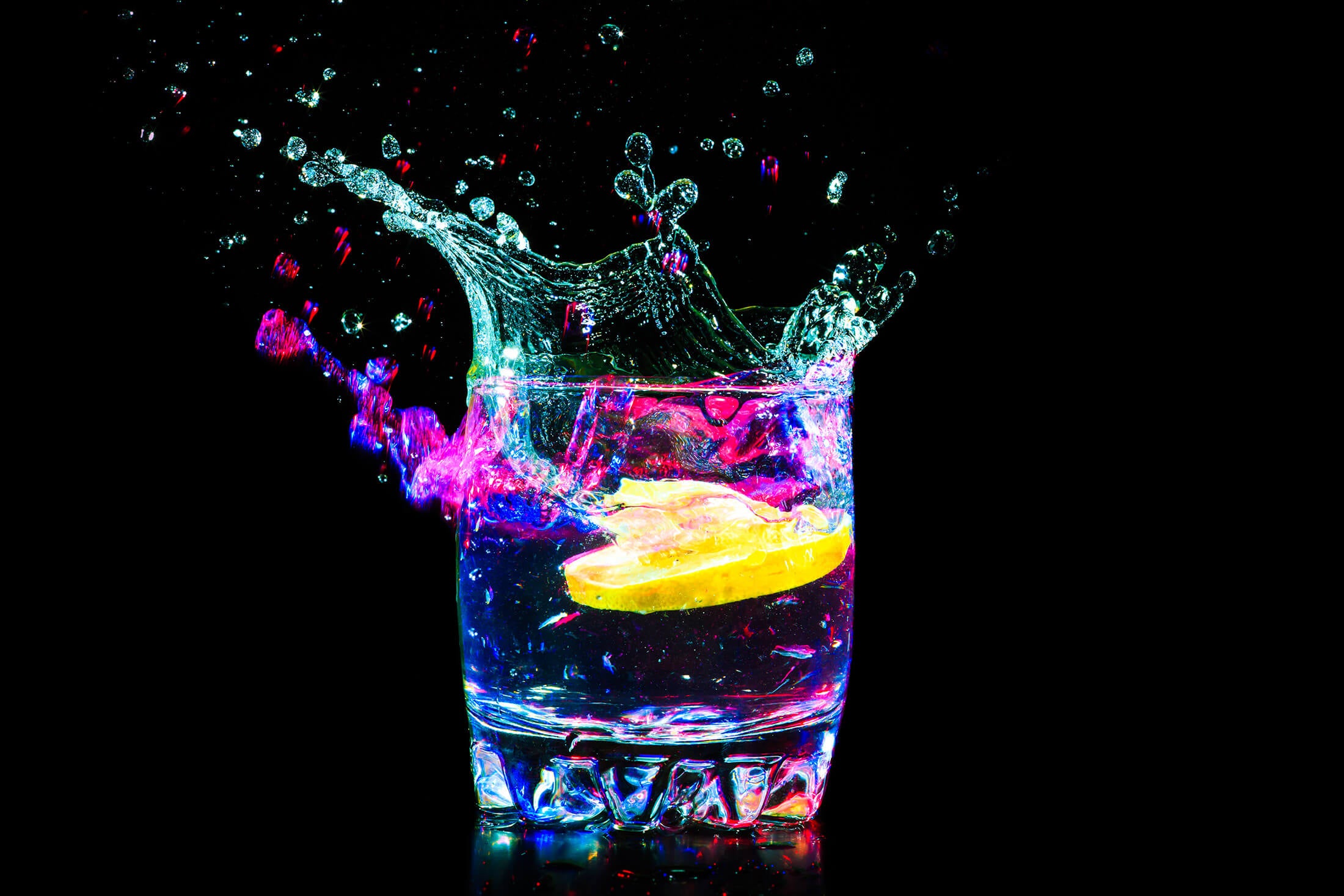 lemon slice dropping into a cocktail glass with liquid splashing in neon colors